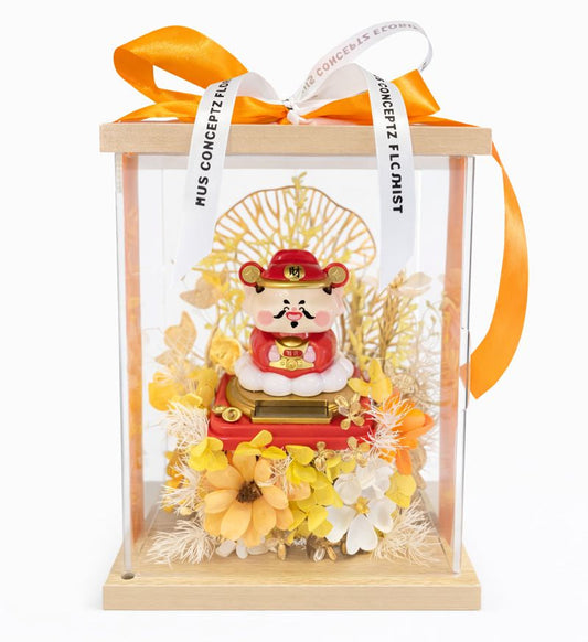 Decorative figure in a clear box with yellow flowers and an orange ribbon on a white background