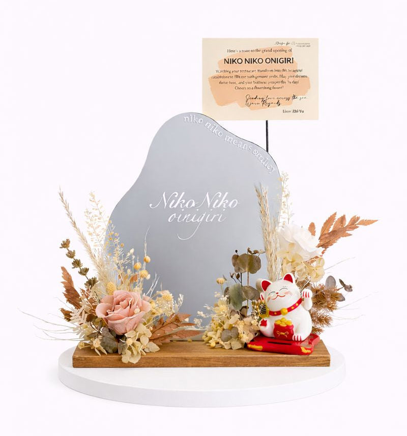 Decorative arrangement with a small mirror, fortune cat figurines, and flowers on a white background.